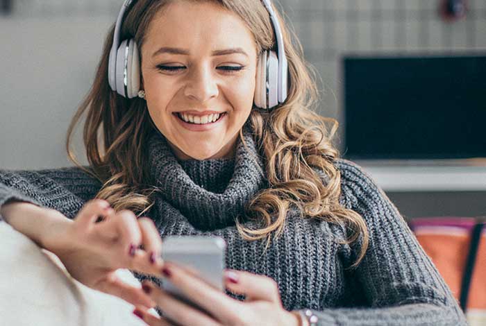 Une femme portant des écouteurs sourit lors d'une conversation téléphonique.