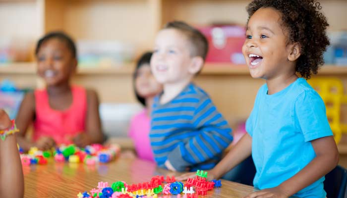 Un groupe d'enfants prennent place autour d'une table dans une garderie.