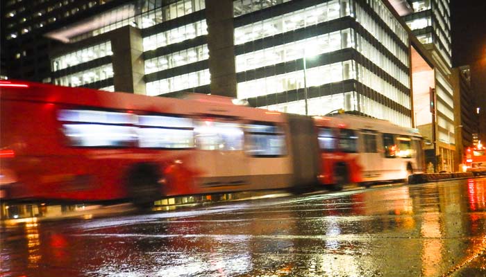 Un autobus circule au centre-ville d'Ottawa par une soirée pluvieuse.