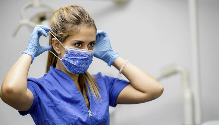 Une professionnelle de la santé ajuste son masque protecteur.