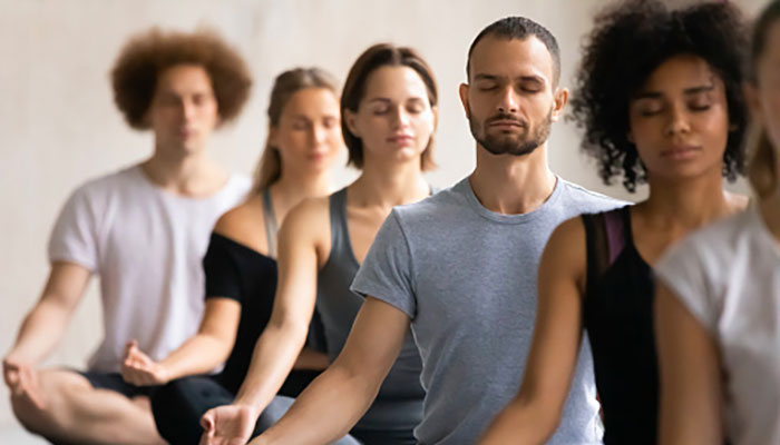 Un groupe de personnes méditent dans une salle.