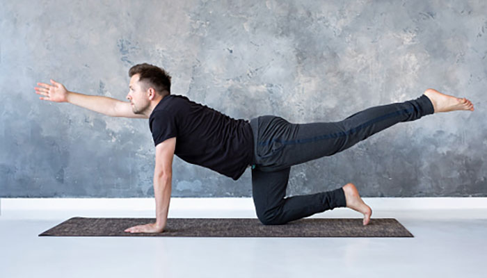 Un homme fait du yoga sur un tapis.