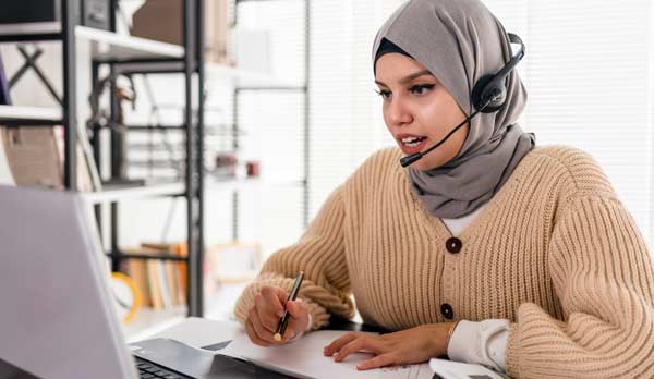 Une femme participe à une rencontre virtuelle à l'aide de son ordinateur portable.