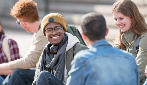 Un groupe d'étudiants discutent et rient à l'extérieur.