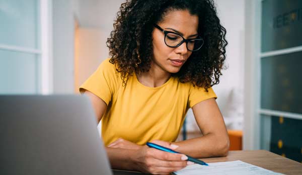 Une femme assise à un bureau consulte des notes.