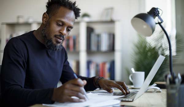 Un homme assis à un bureau consulte des notes.