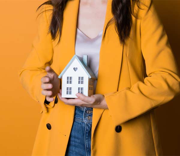 Une femme tient une petite maison de jouets